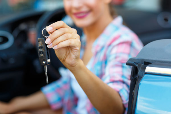 Woman holding a set of keys sitting in a car