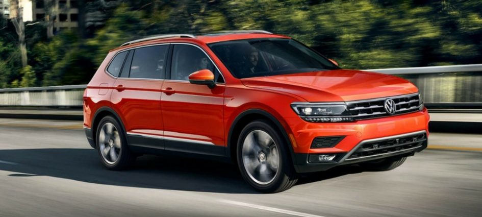 A red 2018 VW Tiguan driving down a road in a blog about VW SUVs