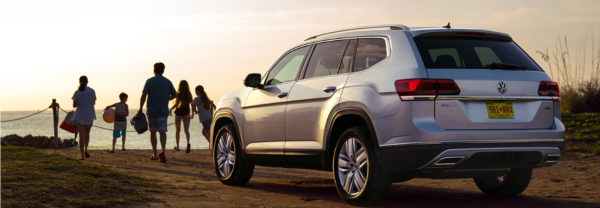 A 2019 Volkswagen Atlas parked at the beach while a family walks toward the water